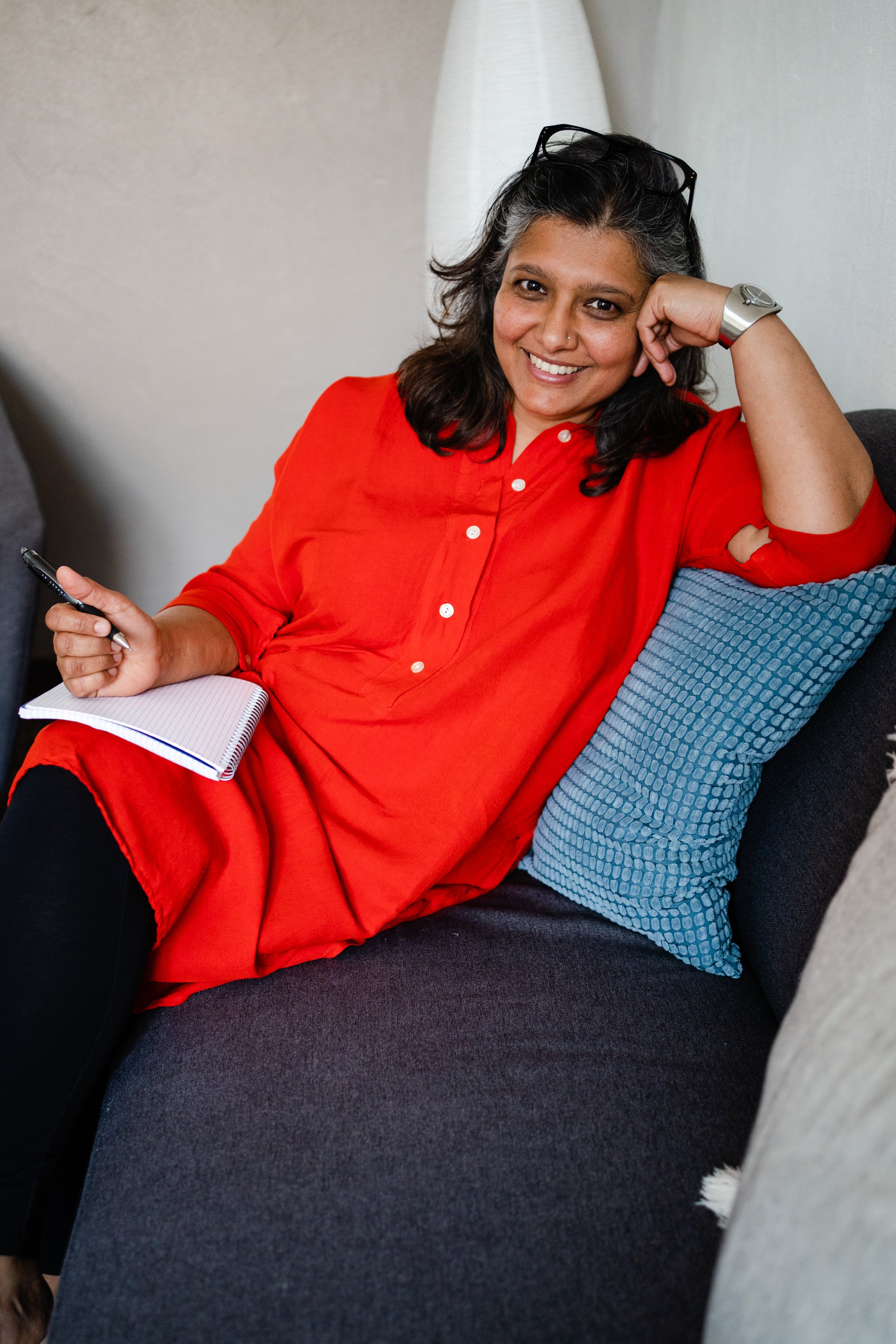 Image of Tanvi Mehta in a red dress with glasses on her head, smiling