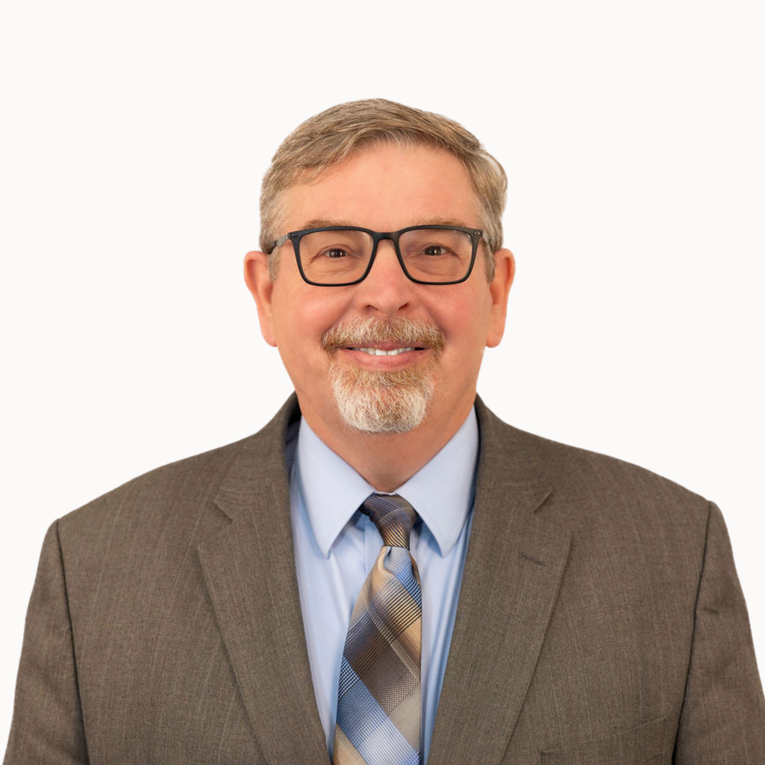 A headshot of a man with brown hair, glasses, a mustache, wearing a black suit, white shirt, and red tie, smiling against a gray background.