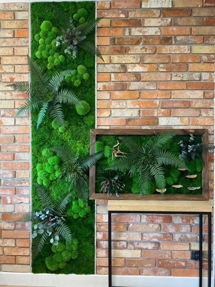 Muro di mattoni con decorazione di piante verdi e muschio, inserita in una cornice di legno e supportata da una struttura metallica