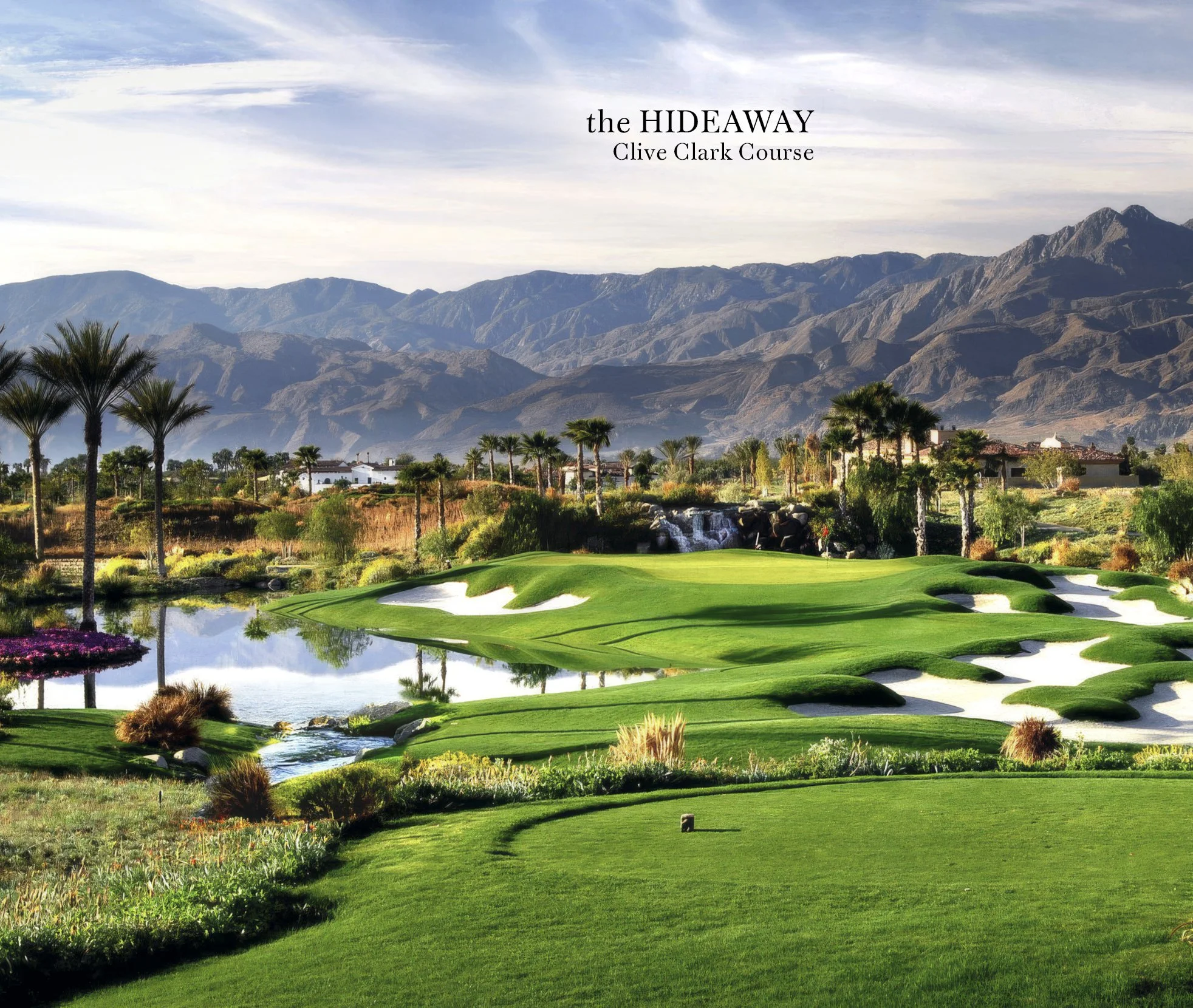 Scenic view of a golf course with green fairways, sand traps, and a water hazard, set against a backdrop of mountains and scattered trees, under a partly cloudy sky.