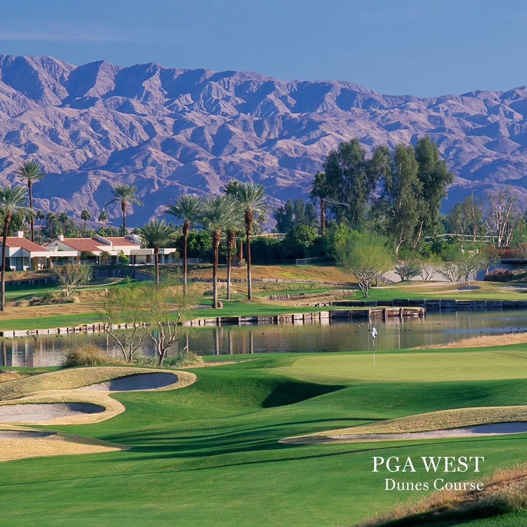 Scenic view of PGA West Dunes Course with palm trees, water hazards, green fairways, and mountainous desert terrain in the background.