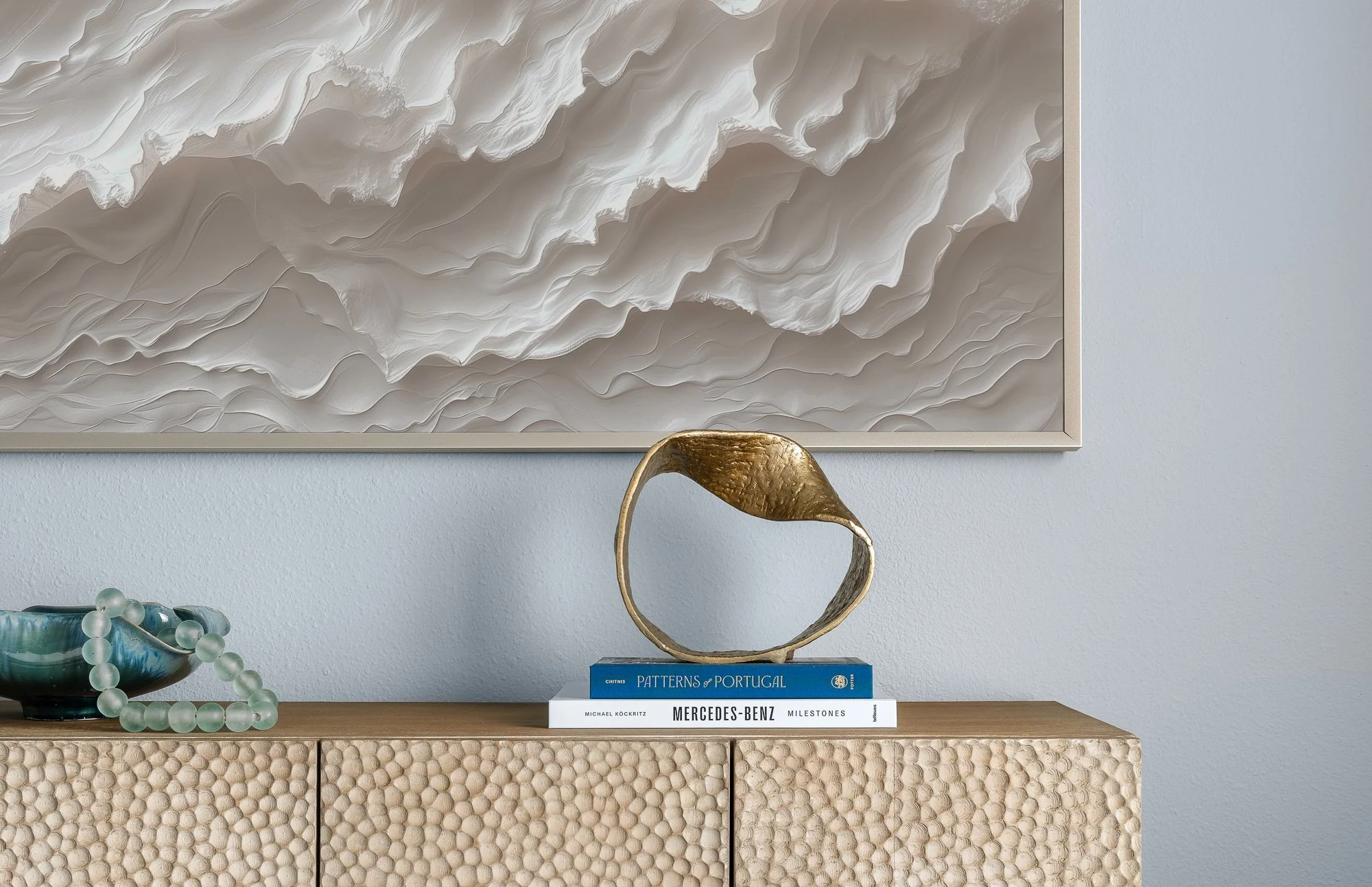 Textured art, bold bronze sculpture on a bronze-colored console table with sea glass accessories in a residence styled for transitional modern interiors Tampa Bay.