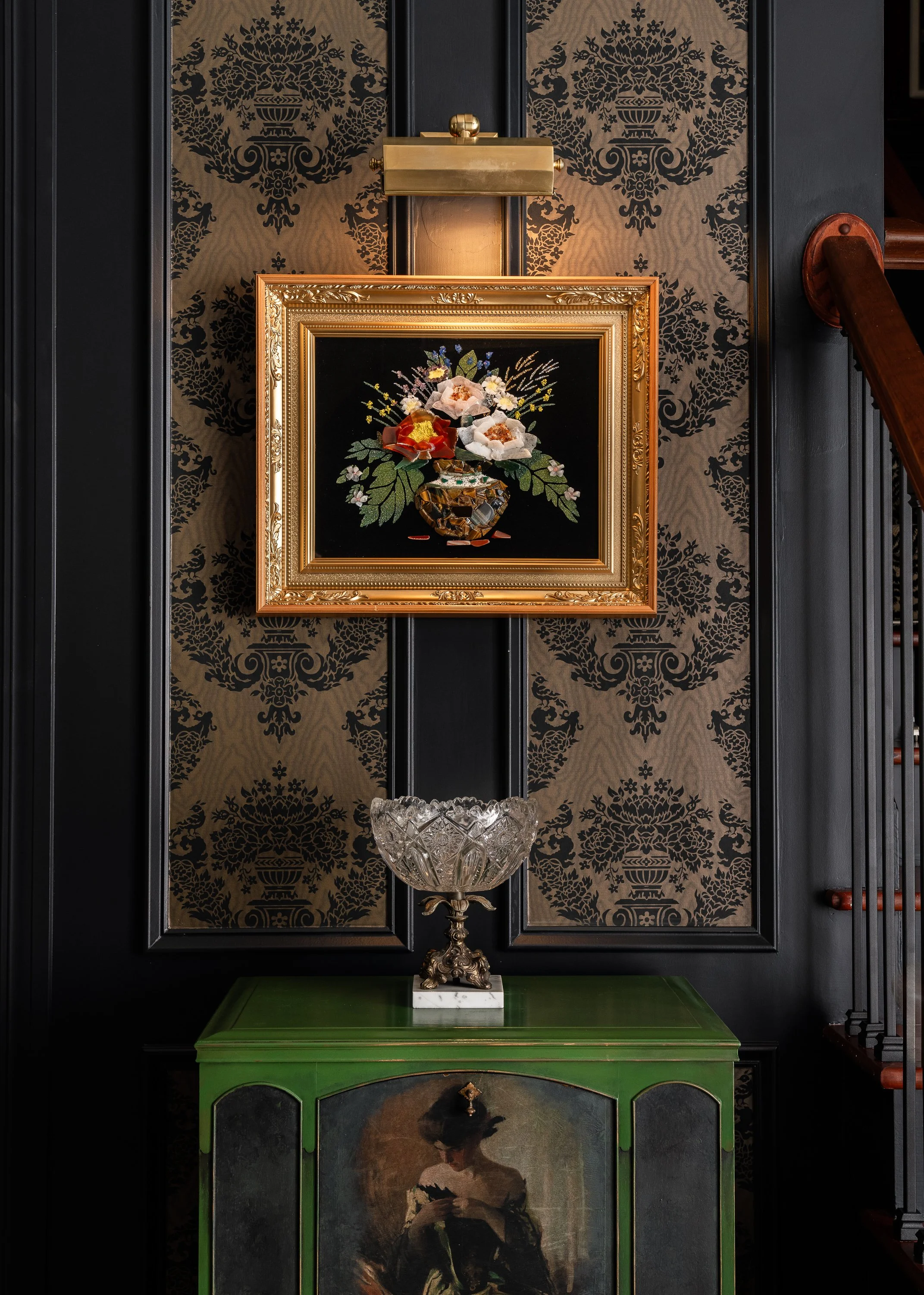 A framed floral tapestry hangs above a crystal bowl on a green cabinet against a damask wallpaper background. Carrollwood Area, Tampa, FL