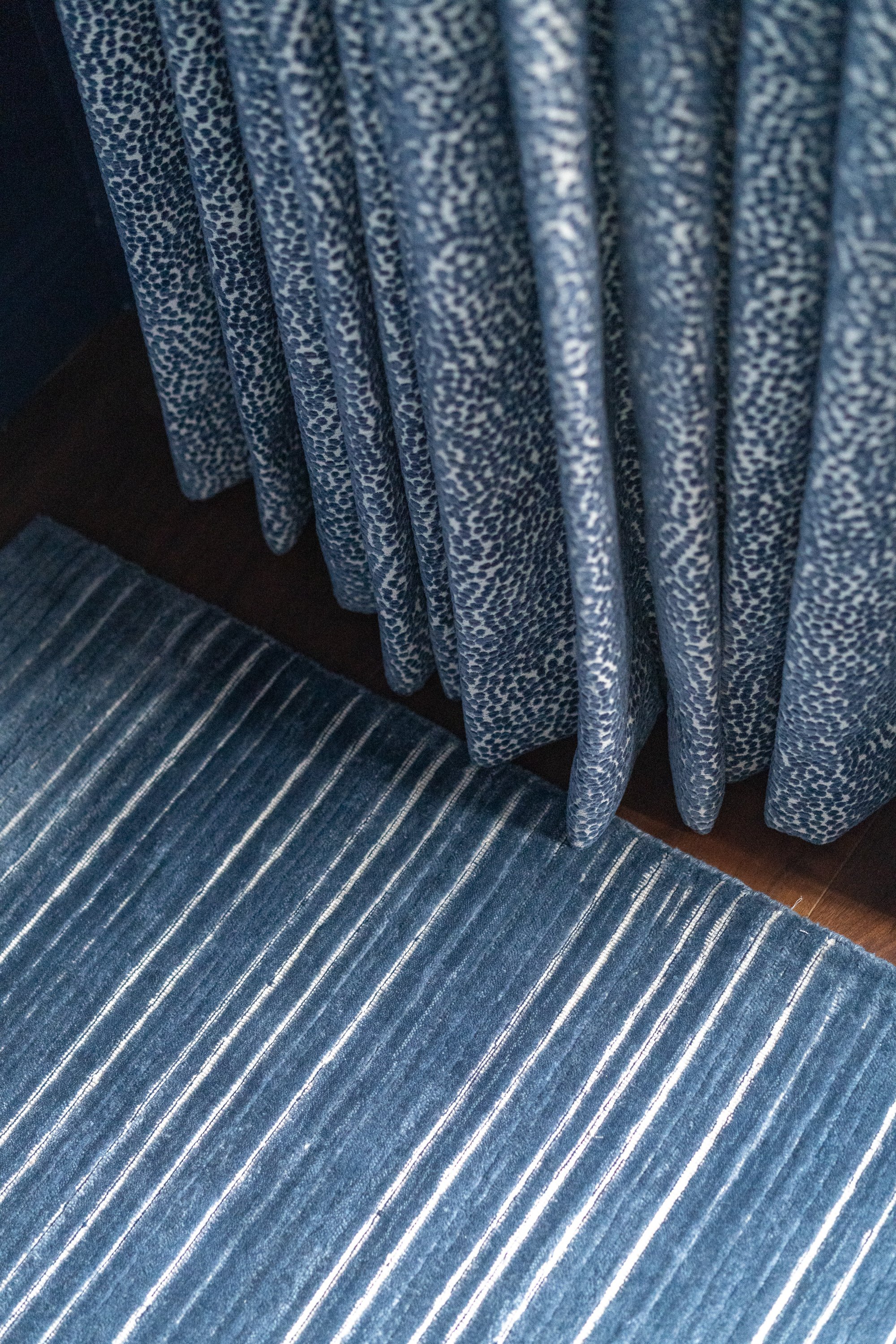 Contemporary Modern Sunroom Design. A blue rug with white stripes lies on a dark wood floor next to a blue curtain with a white dotted pattern.