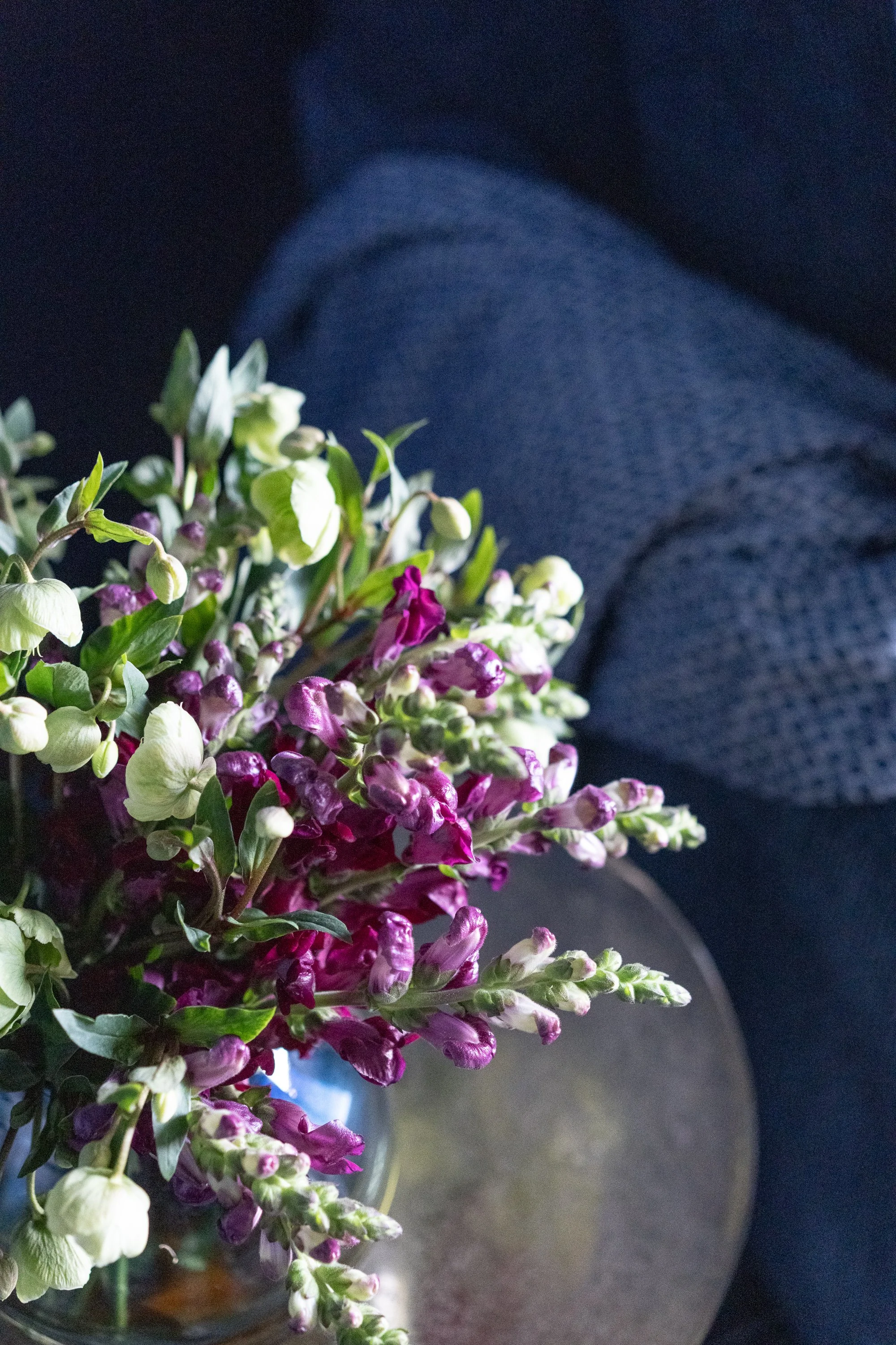 Contemporary Modern Sunroom Design A bouquet of purple and white flowers in a glass vase, with a textured blue fabric in the background.