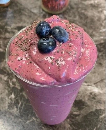 A pink smoothie topped with fresh blueberries and sprinkled with silver and black edible glitter.