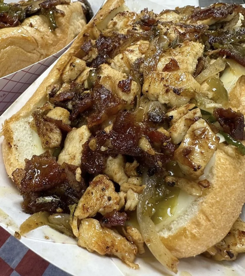 Chicken and bacon sub sandwich with grilled onions on a bun.