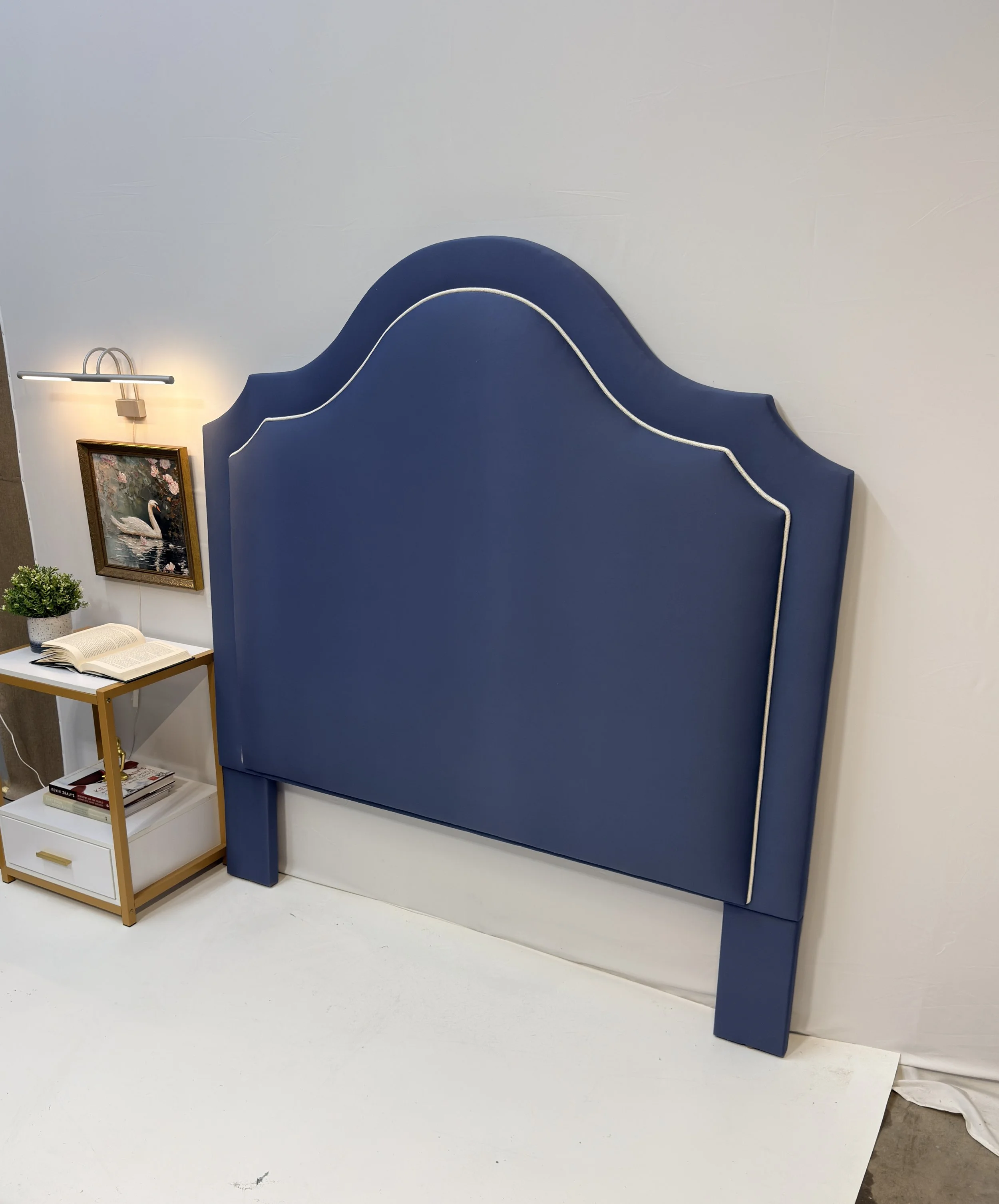 This style features a scalloped camelback or ornate crown silhouette with beautiful contrast piping that highlights the elegant panels rich blue bed frame