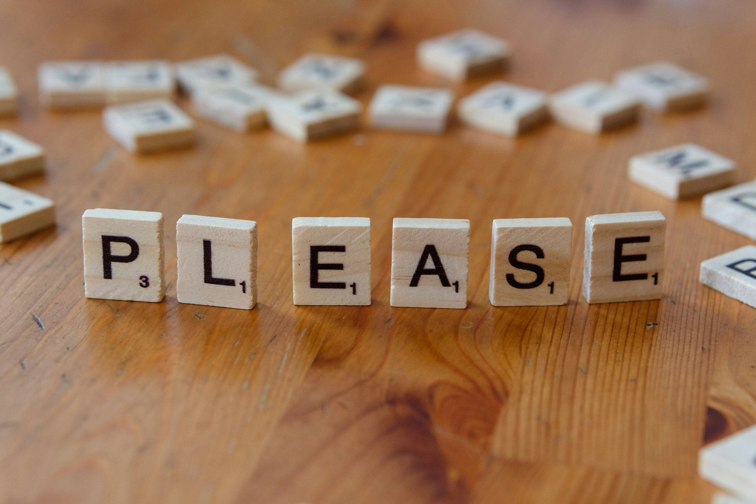 please in scrabble tiles on wood table
