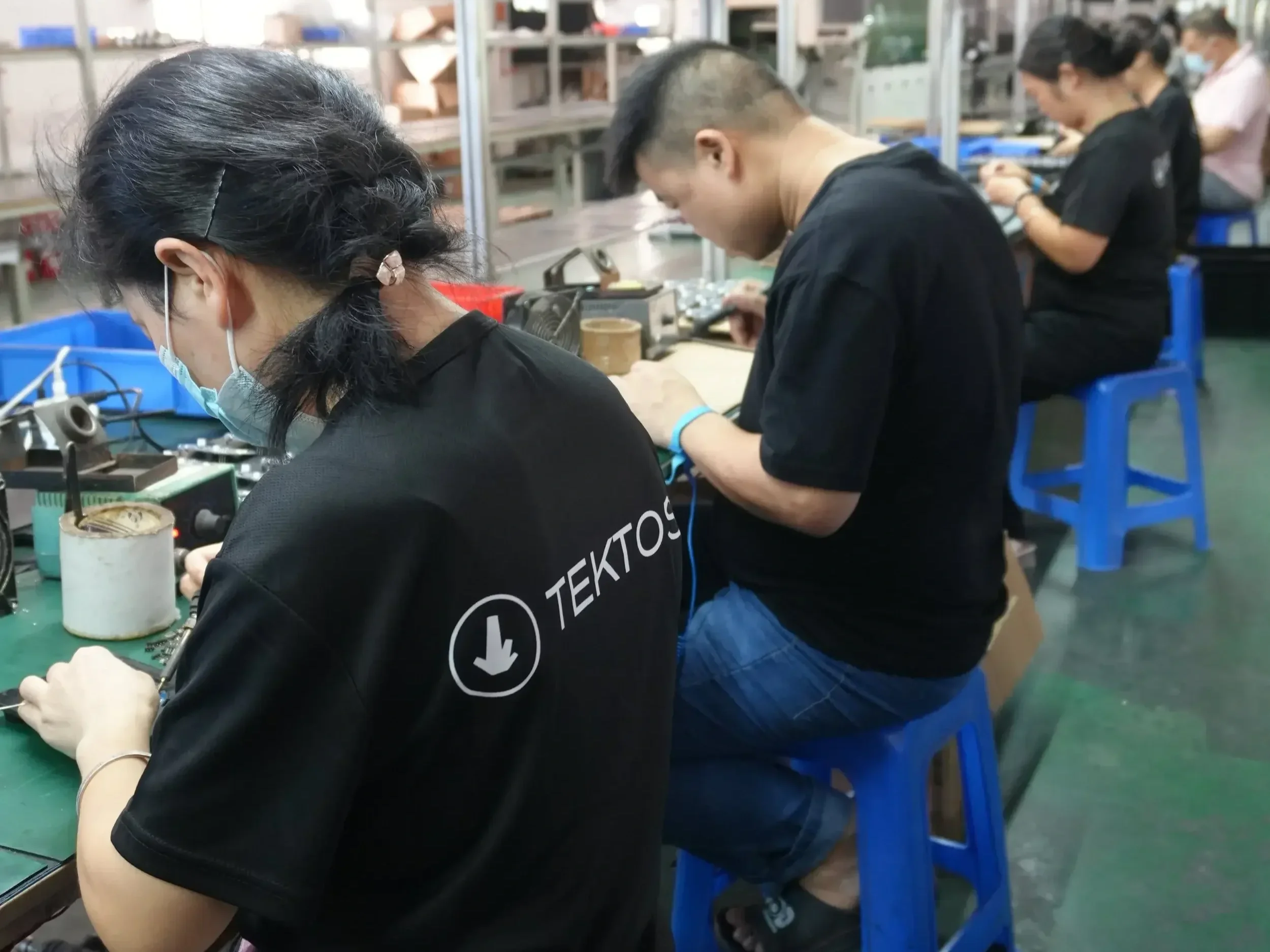 Assembly line workers in TEKTOS shirts conducting product testing and validation