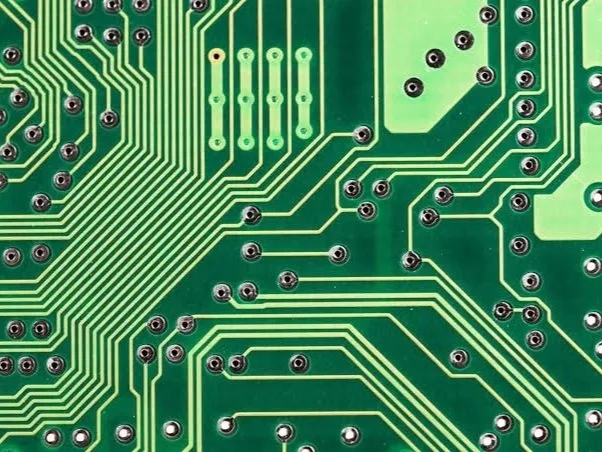 Close-up of green circuit board showing copper traces and electronic routing paths