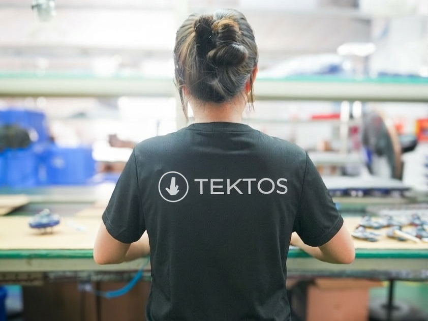 TEKTOS technician performing quality inspection on assembly line production floor