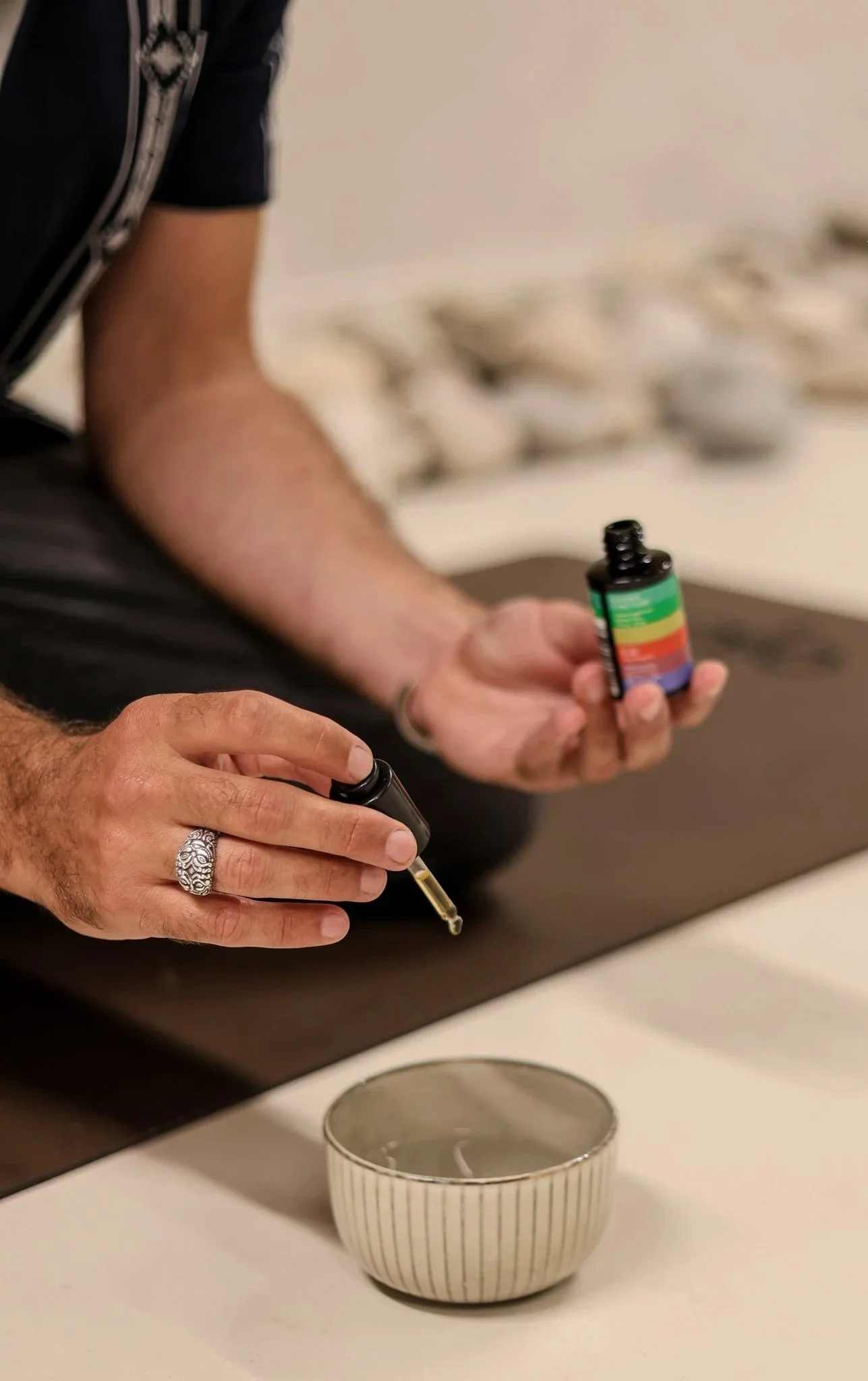 Hand holding a small glass bottle with a dropper, used in psychedelic somatic therapy sessions.