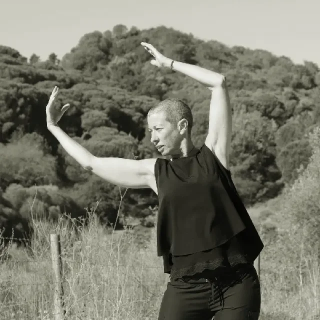 vanda com braços levantados acima da cabeça e o corpo todo inclinado para a esquerda. É um movimento de qi gong chamado varrer o arco-íris