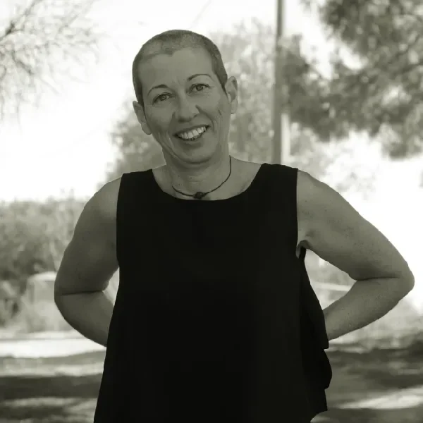 Vanda, foto da cintura para cima, mãos atrás das costas, cabeça ligeiramente inclinada para a esquerda, a sorrir.