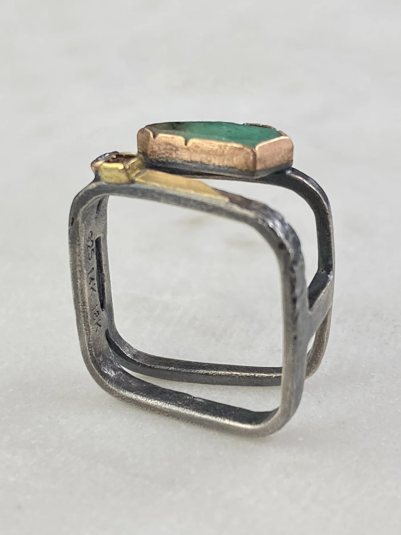 Side profile of a one-of-a-kind geometric statement ring, showcasing the open negative space and sharp, structural lines of the angled square silhouette.