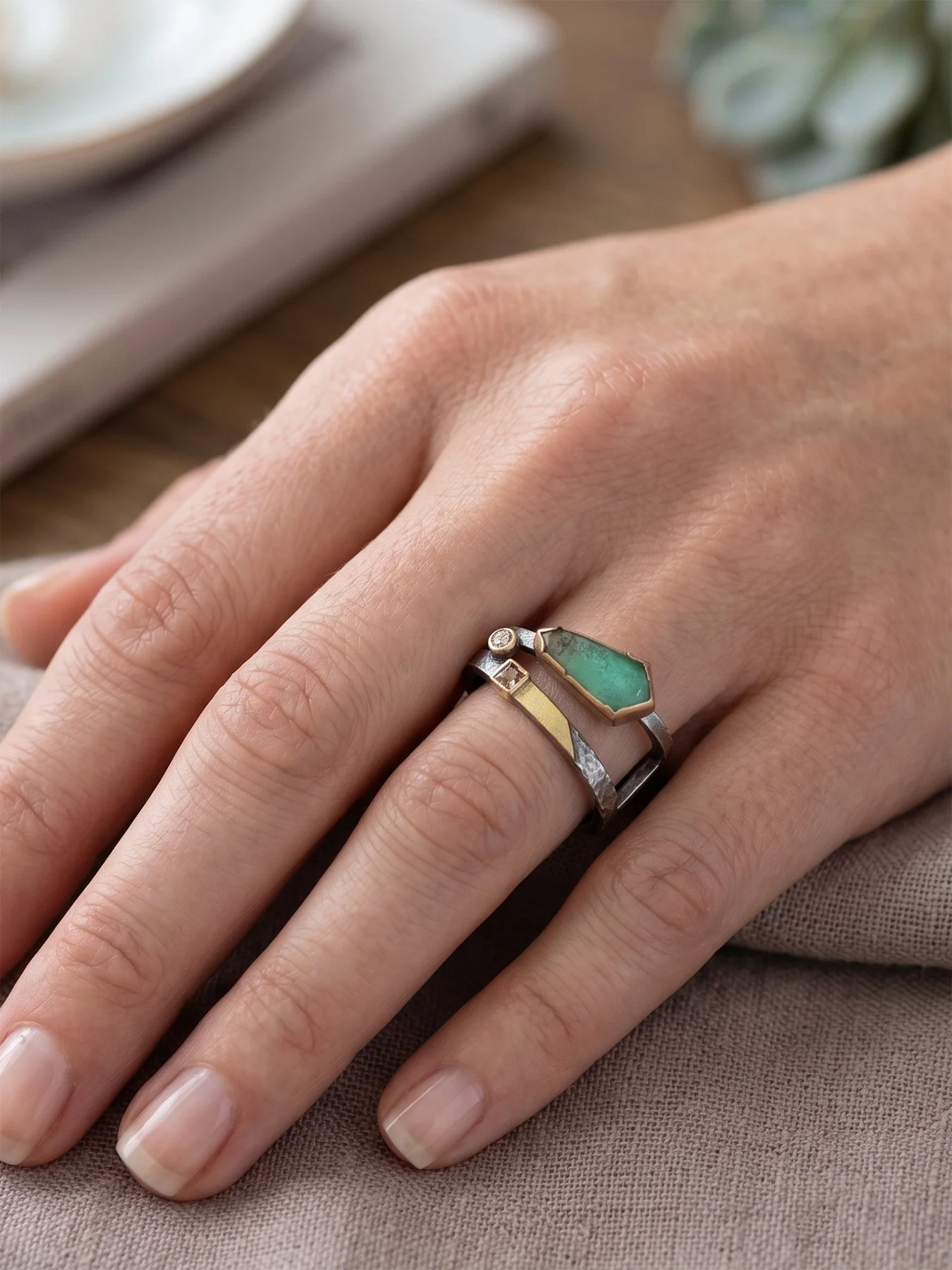 A worn view of the chrysoprase and diamond angled square ring on a hand, demonstrating the scale and striking contemporary design.