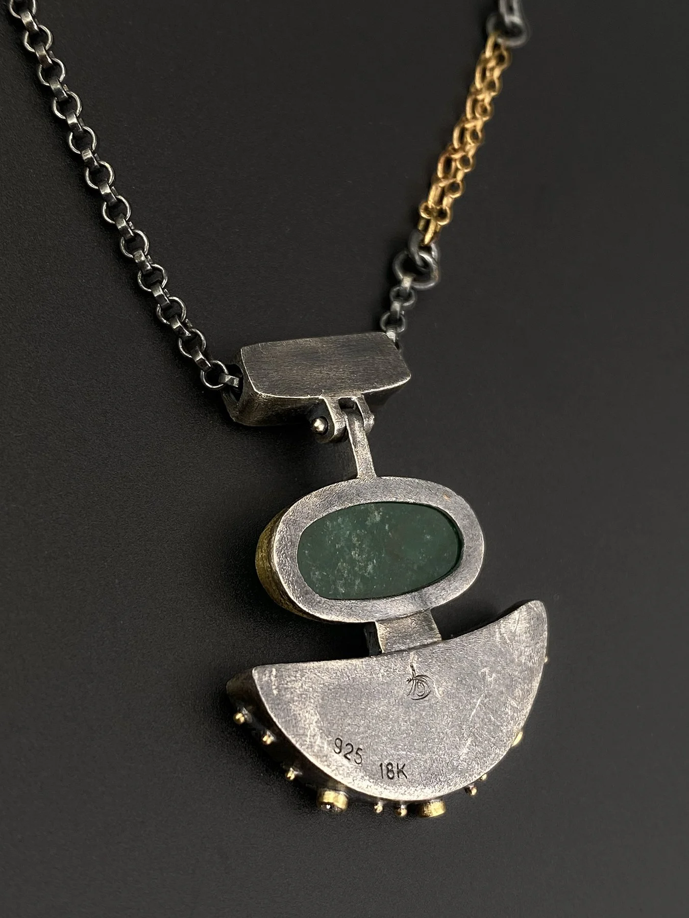 Back view of the handmade emerald and ammonite fossil pendant showcasing the highly secure architectural silver framework and artisan craftsmanship.