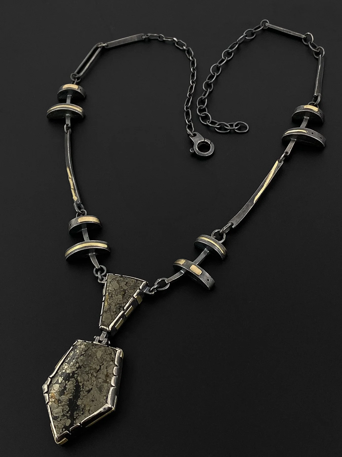 Handcrafted oxidized silver and 18k gold necklace with articulated links and a chalcopyrite stone cut in two and hinged together as a moving pendant.