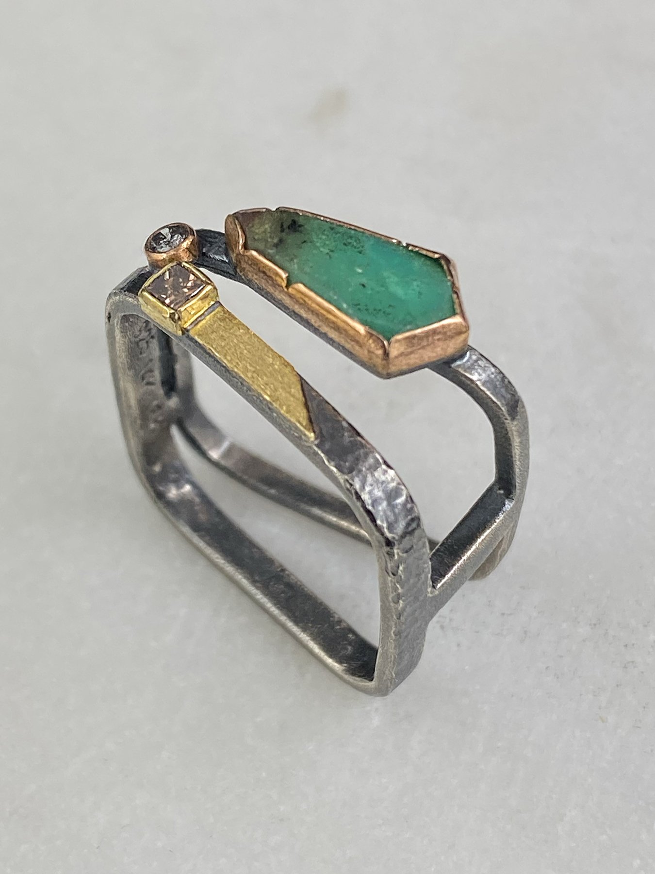 Close-up of a vivid 1.1-carat green chrysoprase stone set in a warm gold bezel, resting on the top structural bar of a geometric mixed-metal ring.