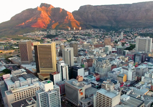 Aerial view of a city with skyscrapers in the foreground and a large mountainous backdrop.