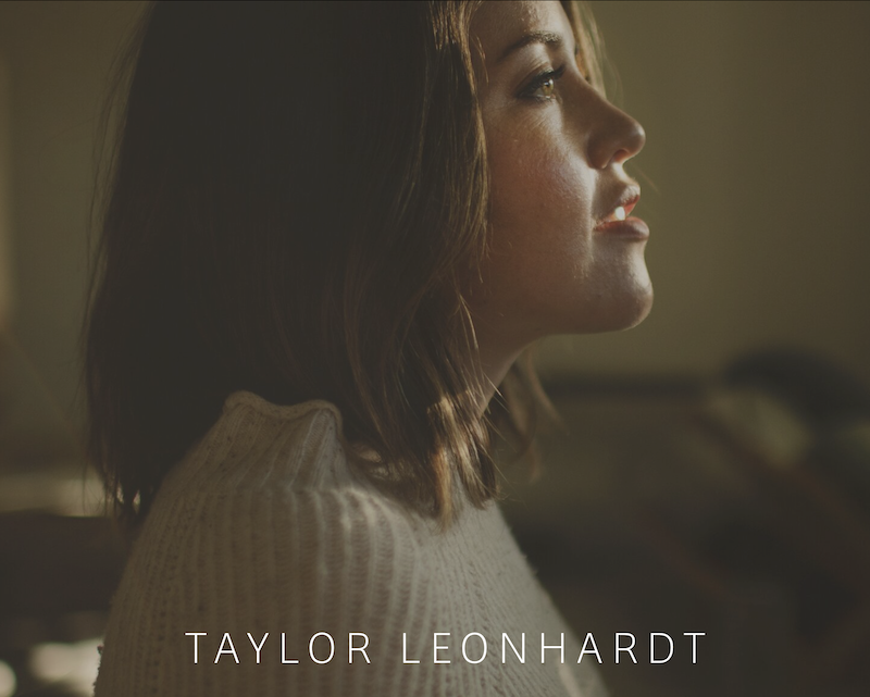 Side profile of a woman in a dimly lit room wearing a white sweater, with the text "Taylor Leonhardt" overlaid at the bottom.