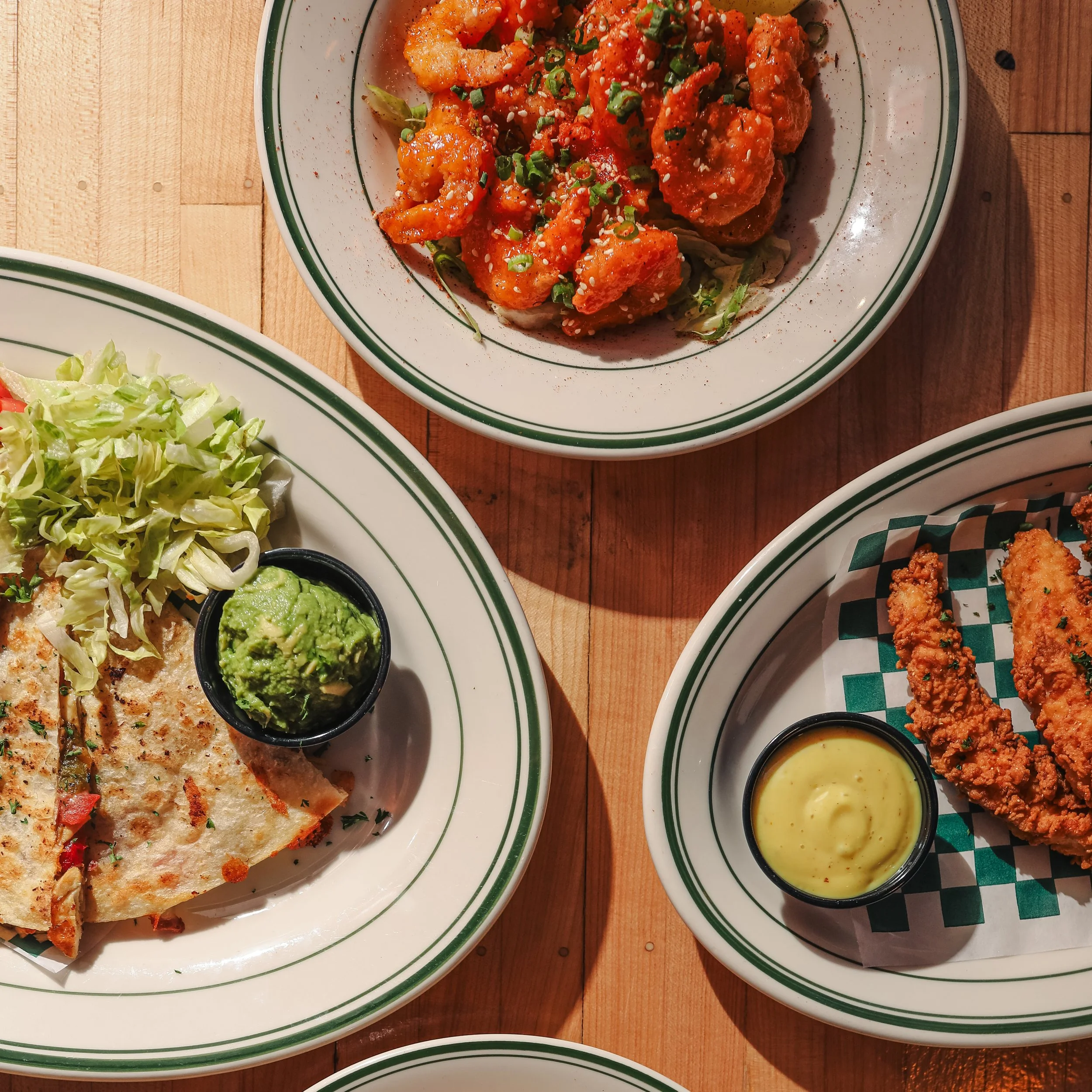 Assorted dishes including fries, chicken wings, potato skins, and dipping sauces on a wooden table.