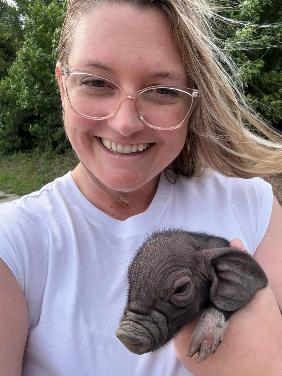 Shannon smiling holding a baby pig.