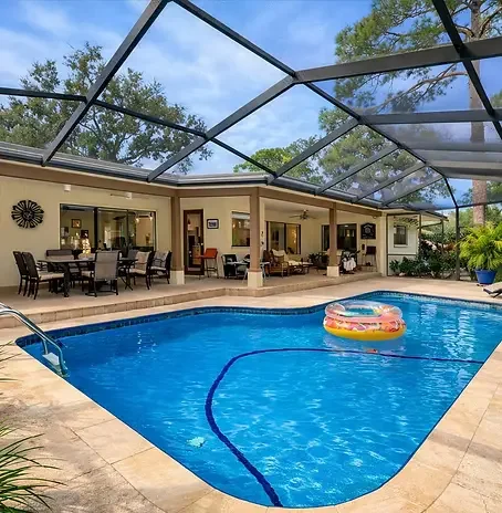 PALM RESERVE Screened-in outdoor swimming pool and patio at Palm Reserve in Dunedin, Florida — featuring a crystal-clear pool, outdoor dining table, and tropical palm surround, offering a private oasis to unwind after a guided ride with Paradise Life