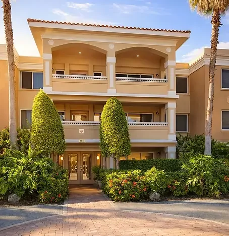 PENTHOUSE Luxurious multi-story condo building exterior at Dunedin Penthouse vacation rental in Dunedin, Florida — featuring private balconies and palm-lined grounds, offering an upscale basecamp just minutes from local e-bike trails and Paradise Lif