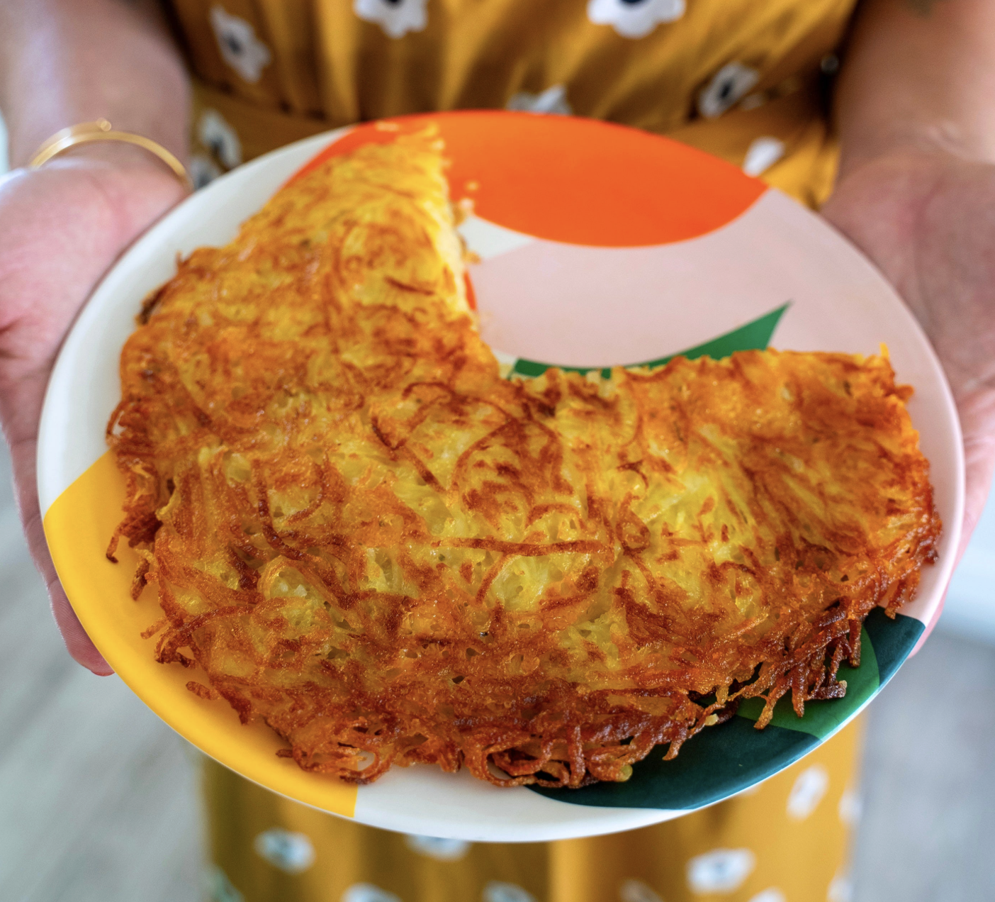 A plate of potato rosti with a slice taken out of it.