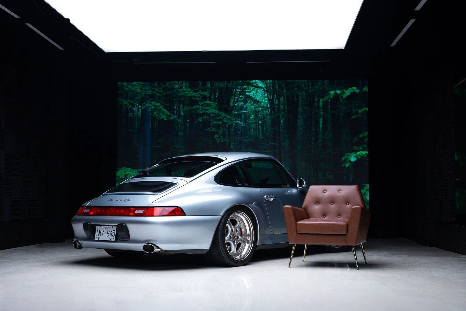 Silver Porsche 911 on the gloss floor with a forest scene on the VFX wall