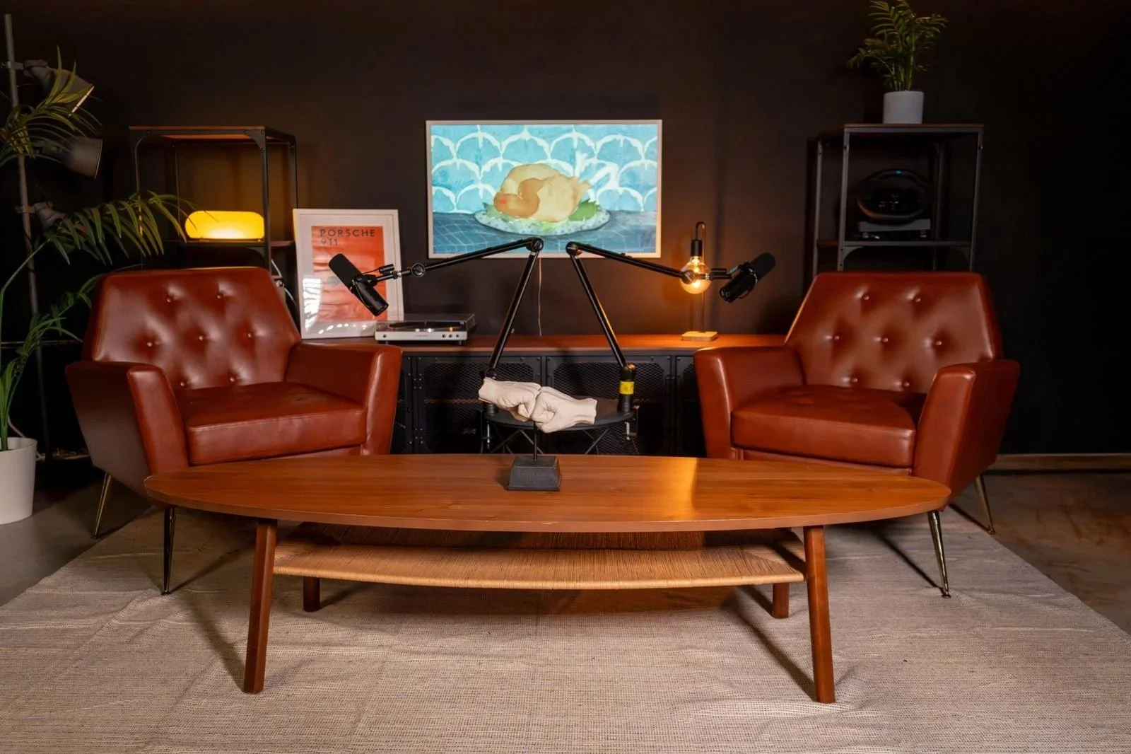 Podcast lounge with two leather chairs, boom mics and coffee table
