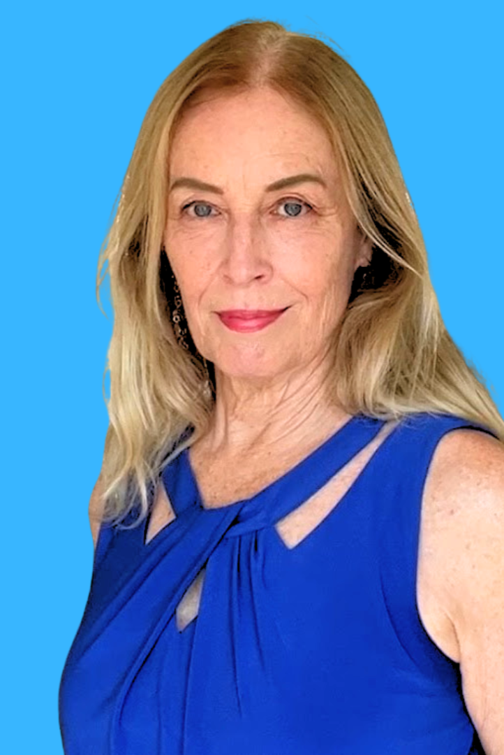 A woman with shoulder-length blonde hair, fair skin, and blue eyes wearing a sleeveless blue dress and earrings, standing against a solid light blue background.