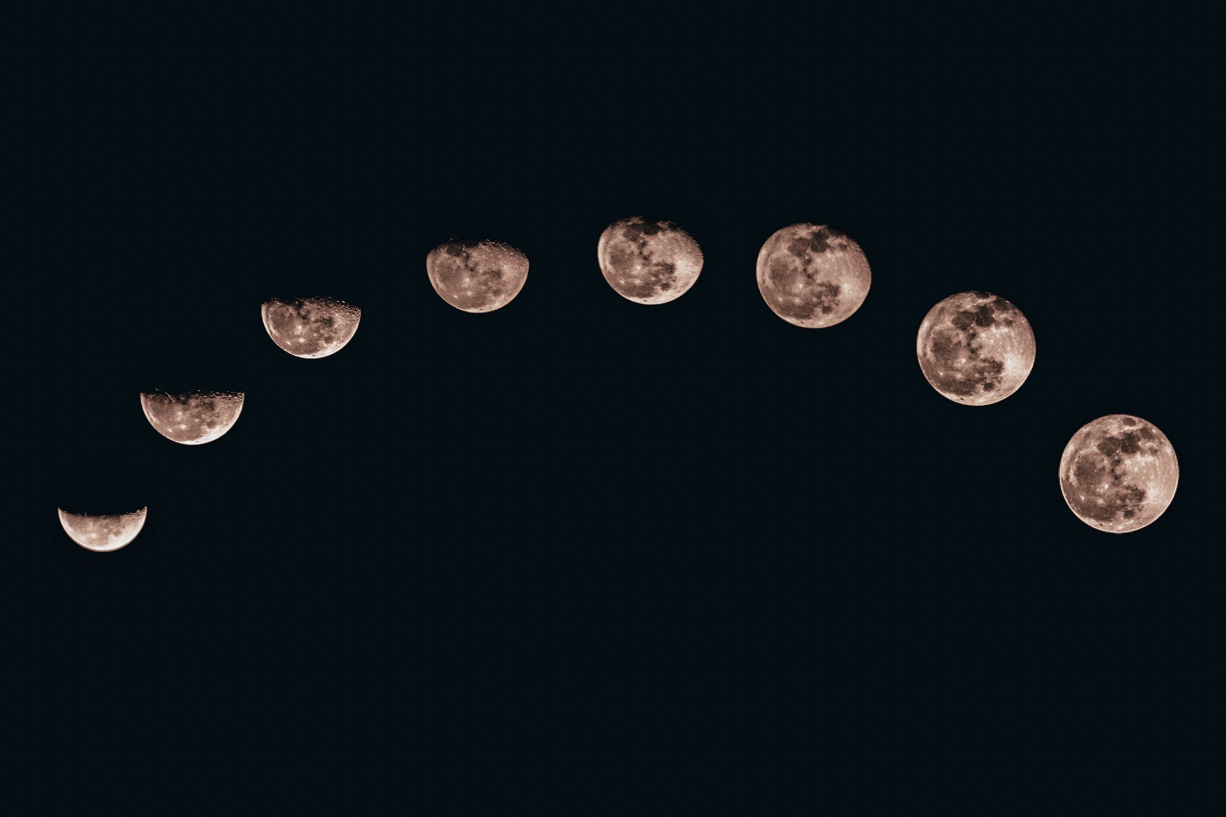 Moon phases progression from crescent to full moon against black background.