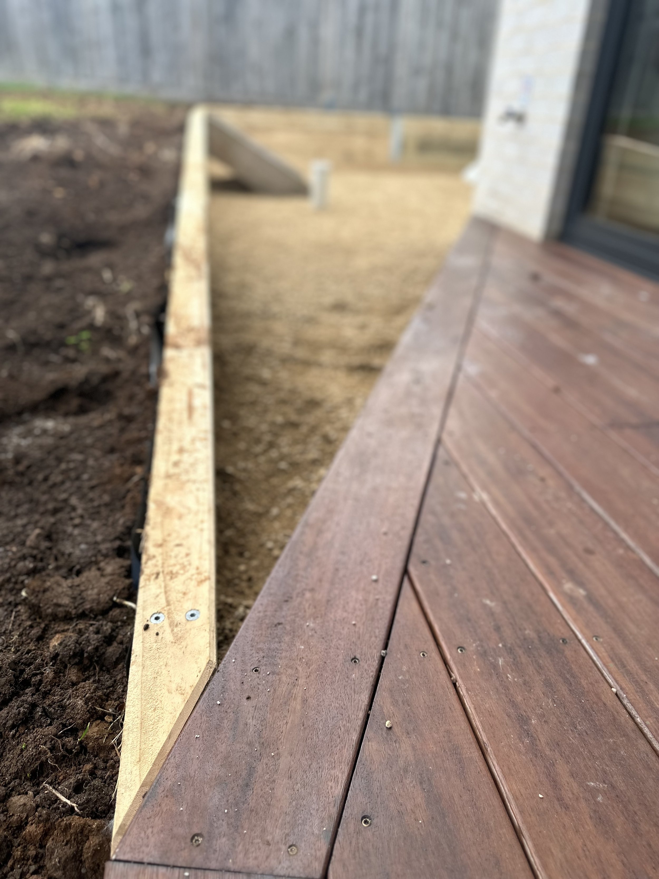 Close-up of a wooden deck with unfinished yard and gravel area