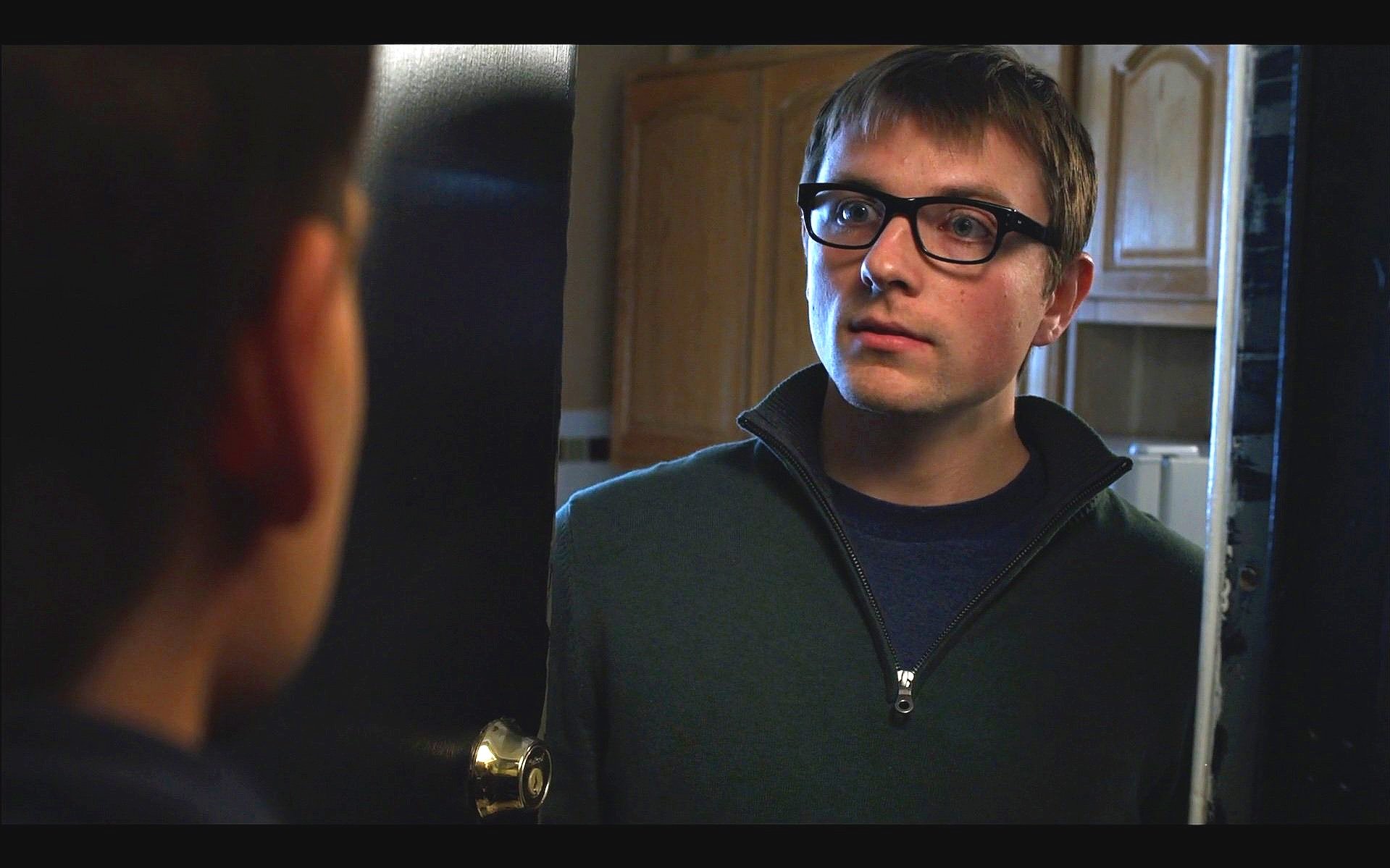 Patrick Murney portraying a character while looking into a mirror during a dramatic scene.