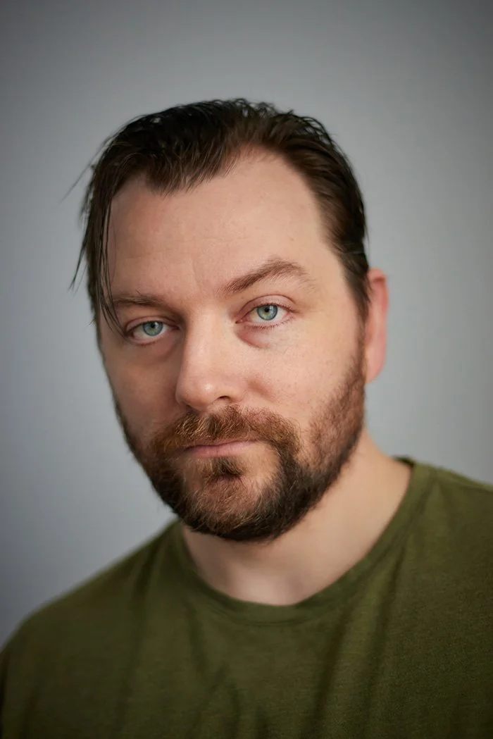 Patrick Murney professional portrait in green shirt against a soft neutral background.