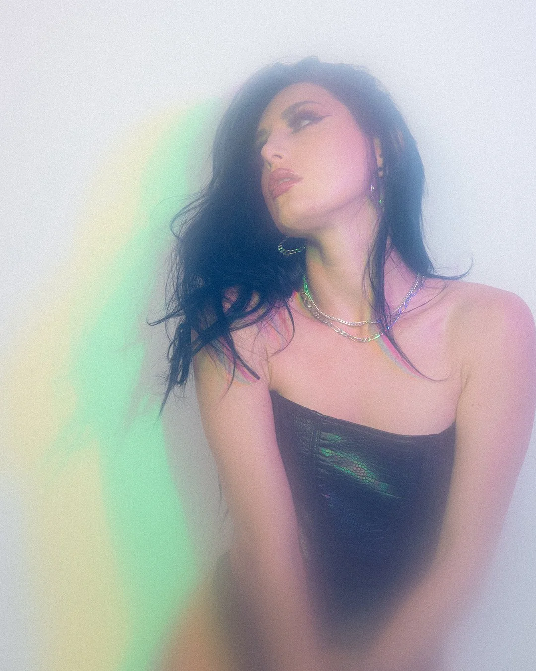 Artistic portrait of a woman in a strapless top, with colorful light reflections.