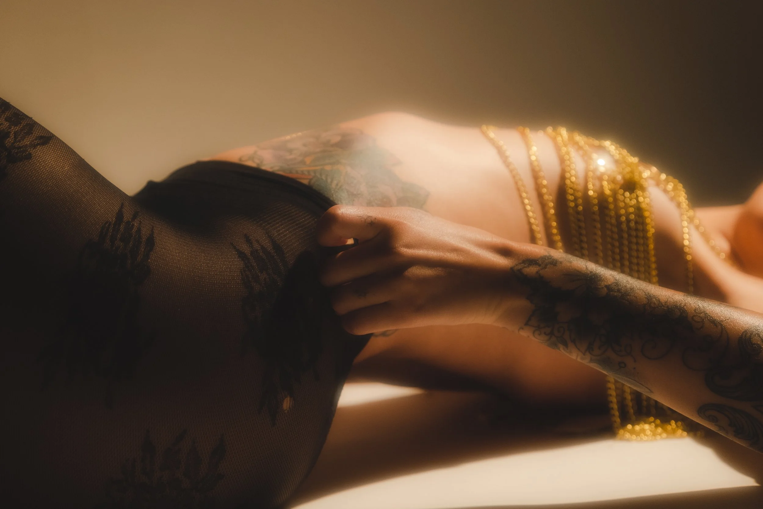 Close-up of a person wearing tattooed, gold chains and black patterned tights