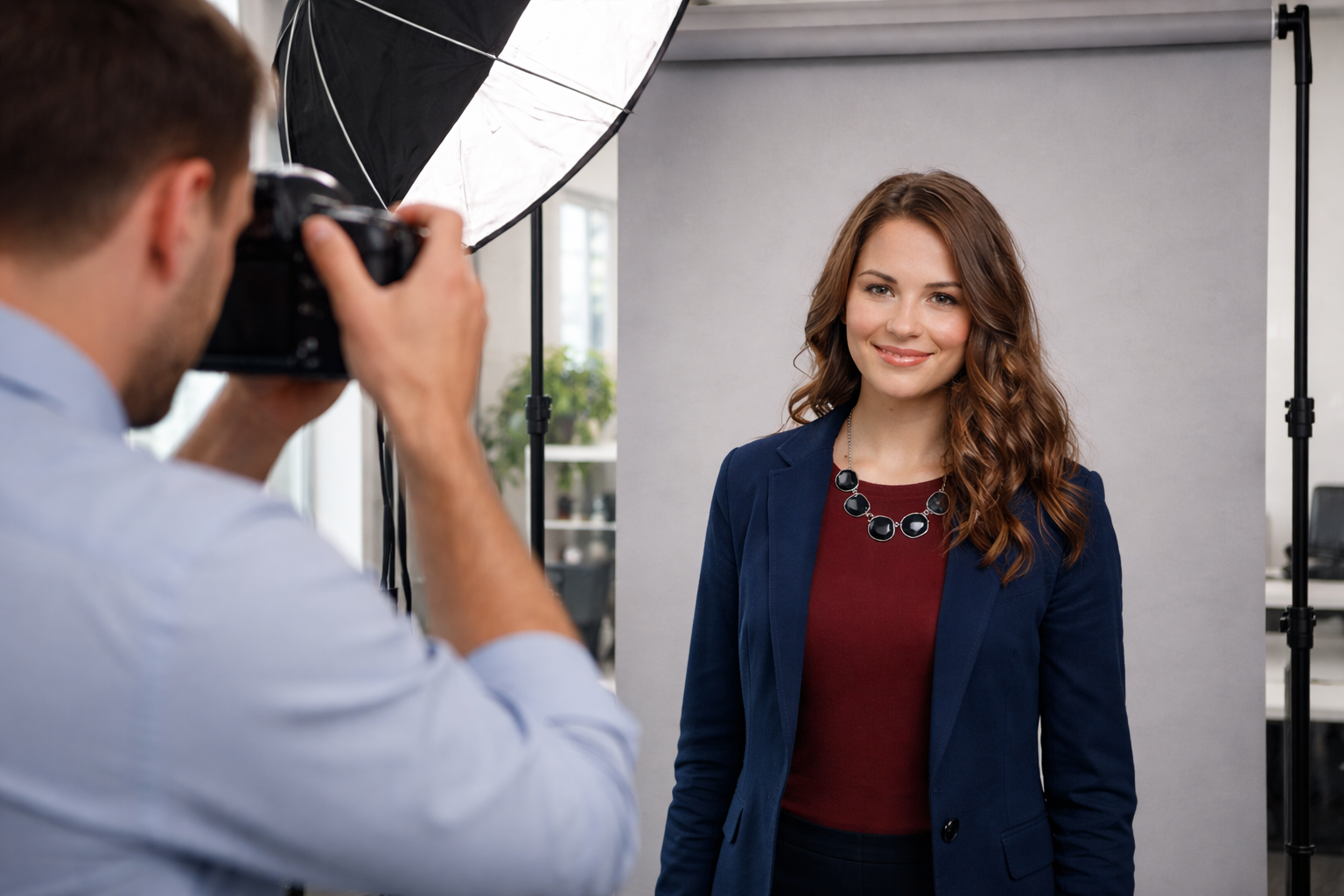 Professional headshot session in an office with a photographer capturing Jennifer Strong in front of a backdrop with studio lighting setup.