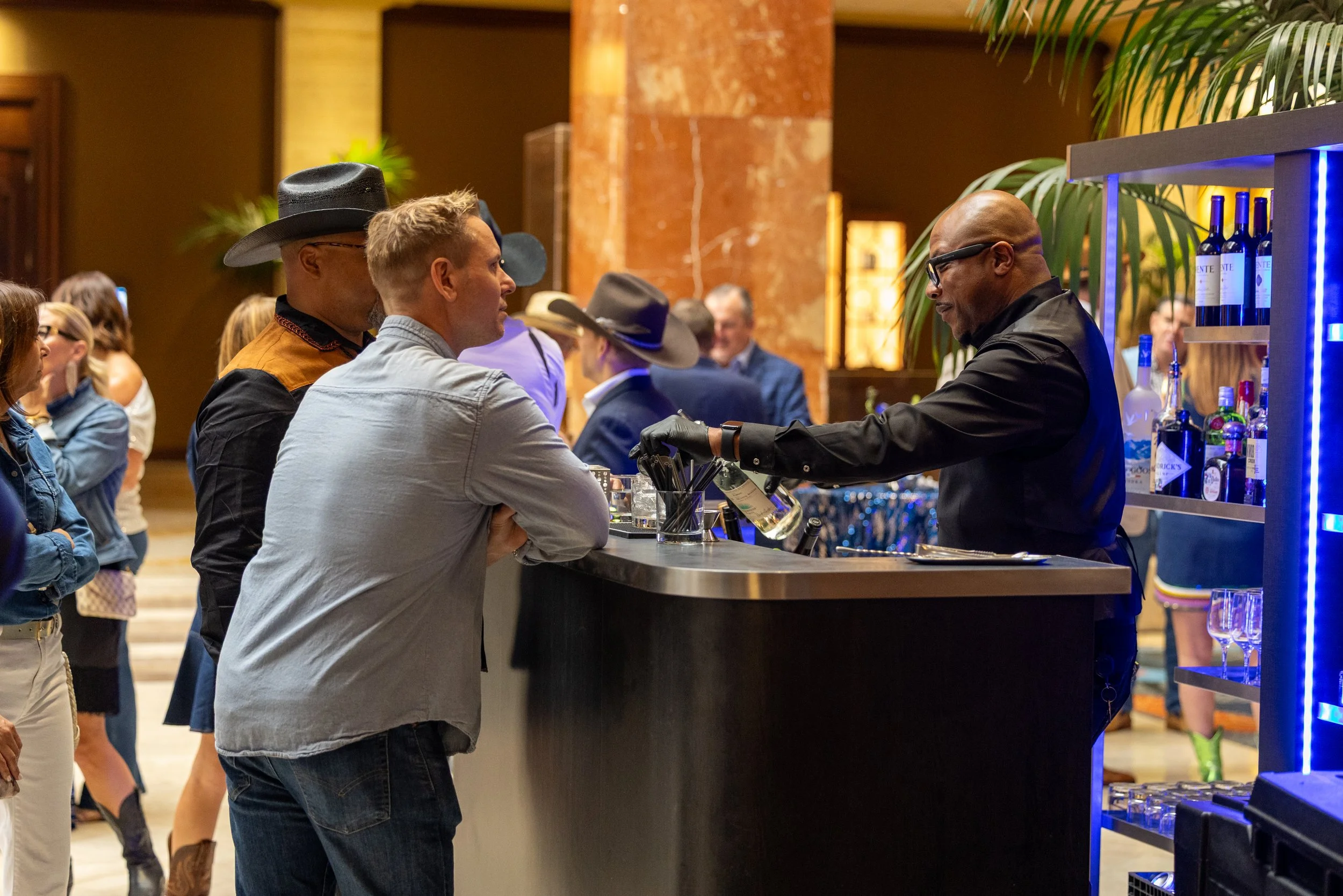 A bartender serving drinks to business professionals during a networking mixer reception at a Texas-themed corporate gala in Dallas-Fort Worth.