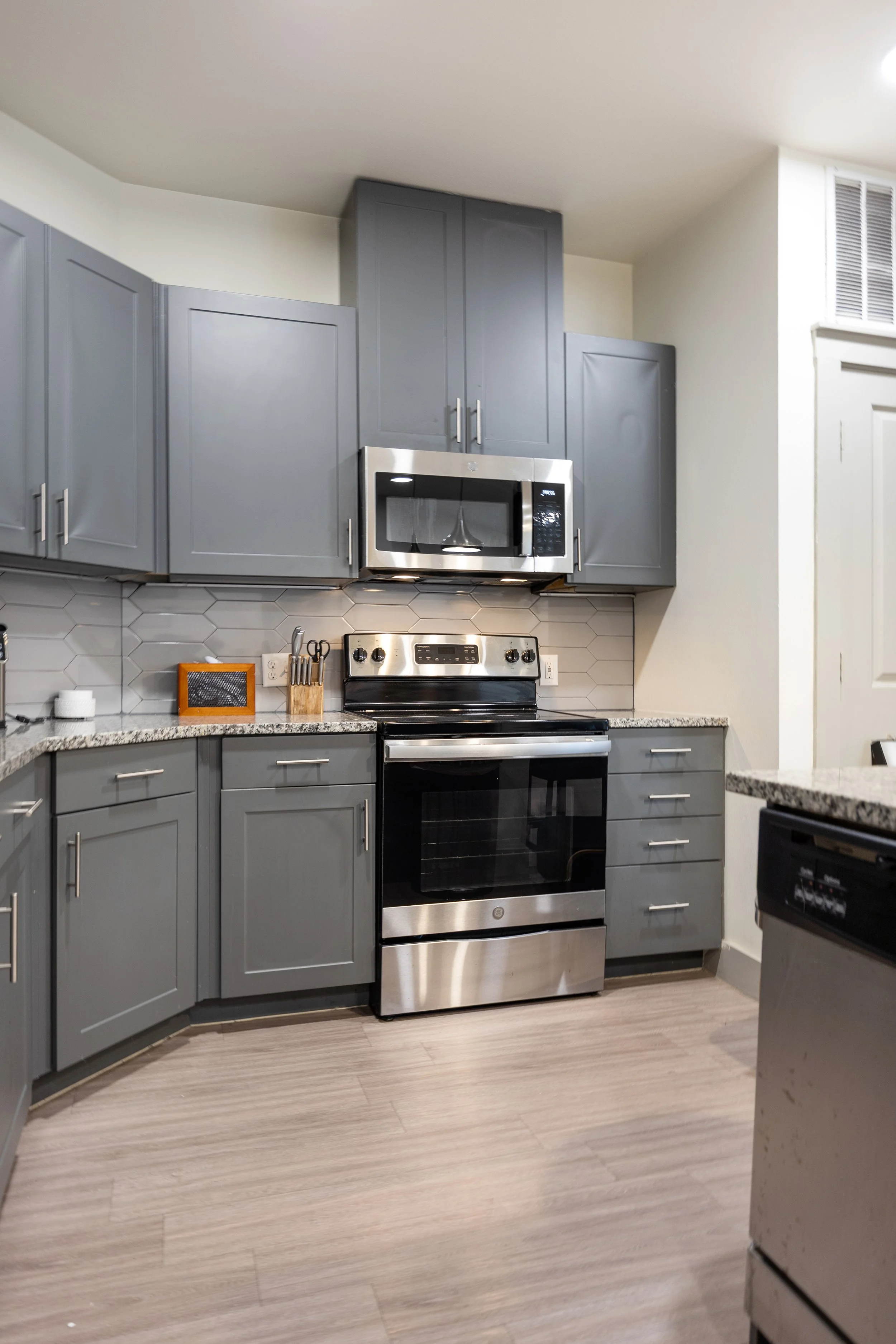 Short-term rental kitchen with stainless steel appliances, gray cabinets, and modern backsplash