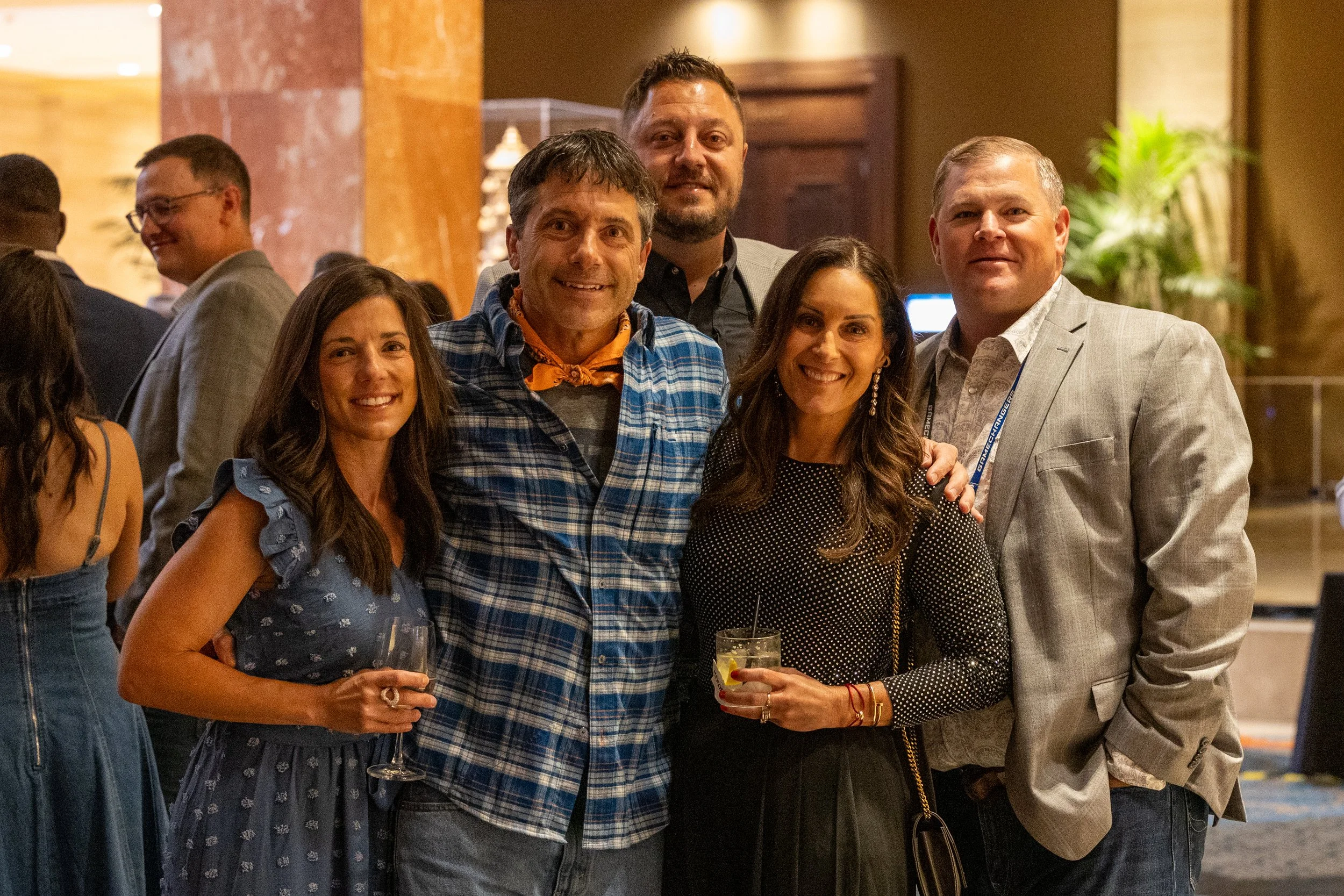 A smiling group of business professionals posing together for a photo during a cocktail reception at a corporate gala in Dallas-Fort Worth.