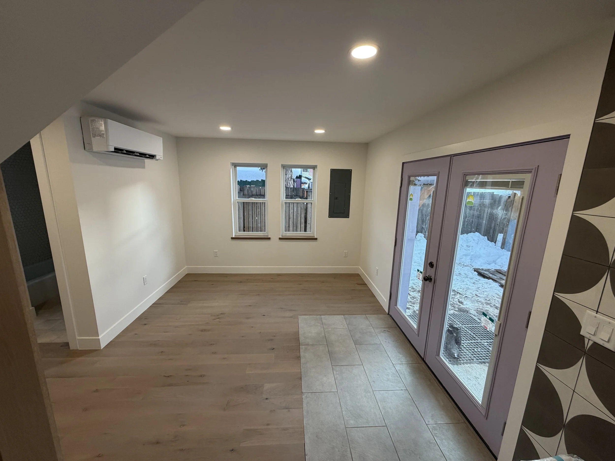 New main level living area with French door, wood floors, tile entry