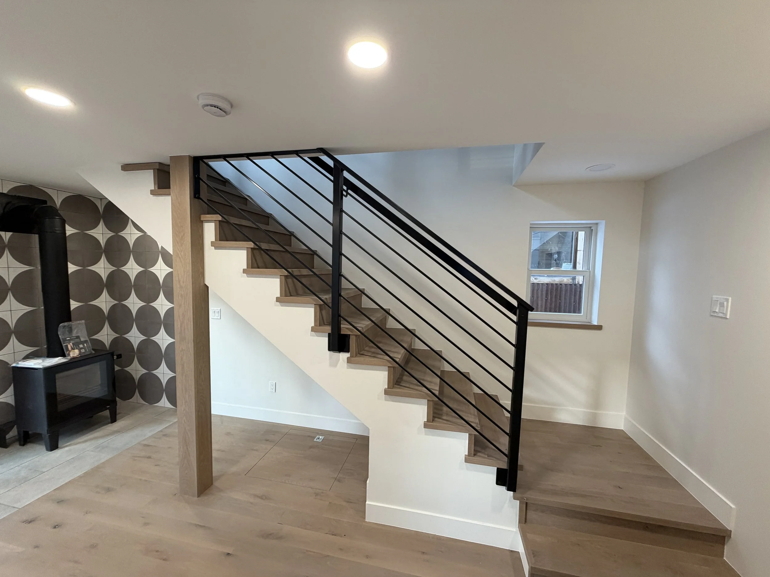 Main level stairway and wood stove with steel banister and tile hearth and stove surround