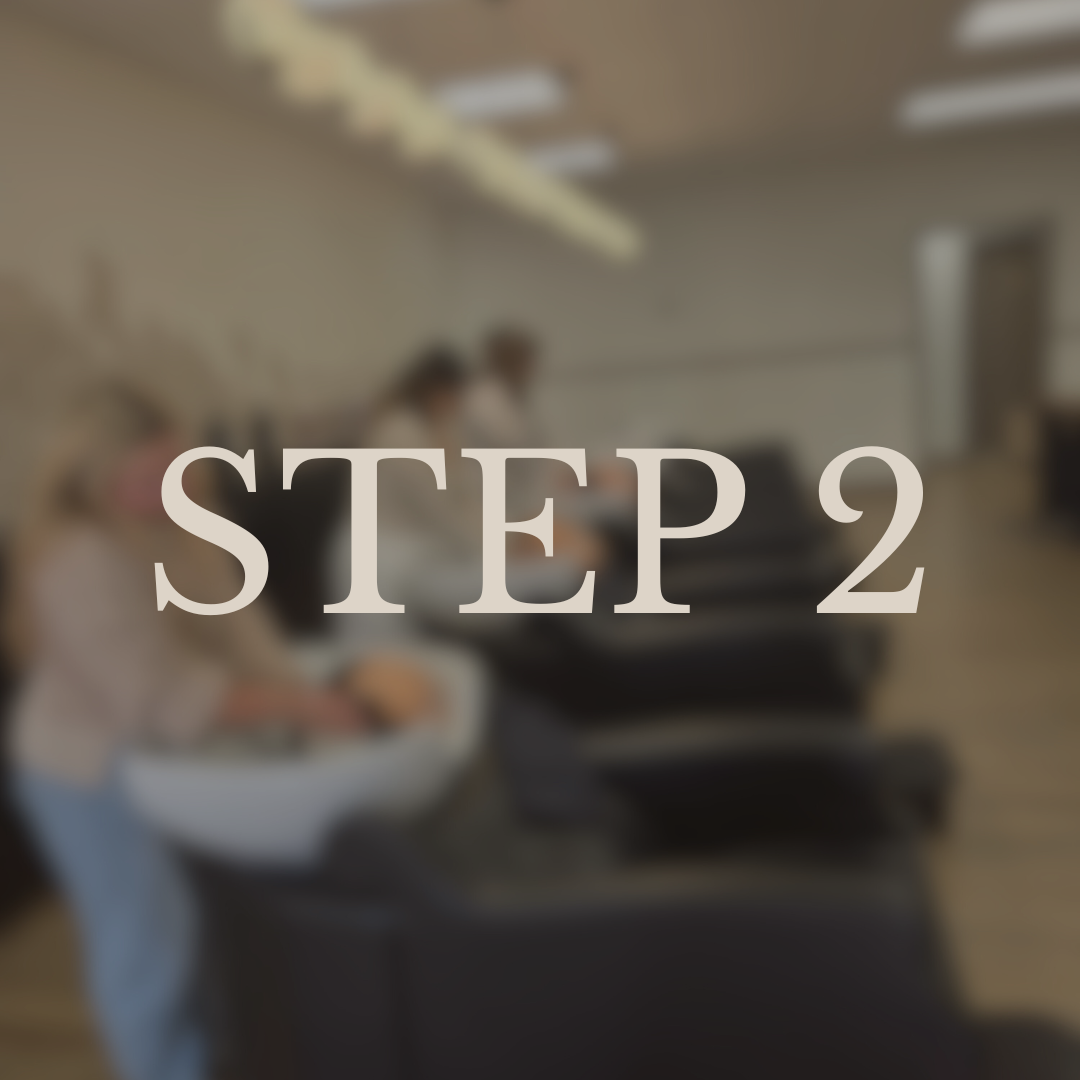 People involved in a food preparation or serving activity in a room, possibly a kitchen or cafeteria, with chairs and tables visible.