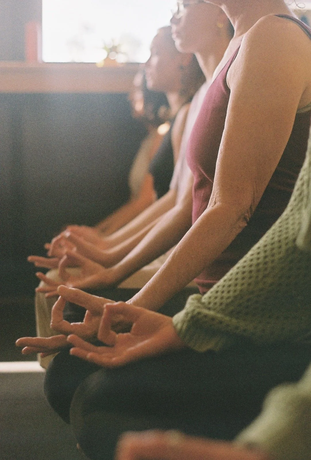Close up of yoga students' hands with index finger and thumb touching to create the Gyan Mudra