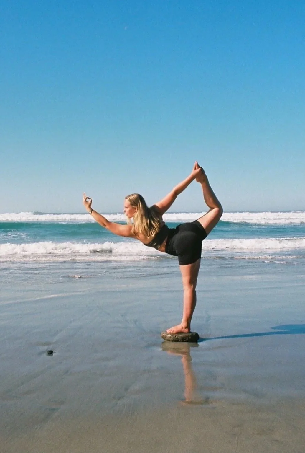 Yoga teacher in Dancer Pose, or Natarajasana, on the beach
