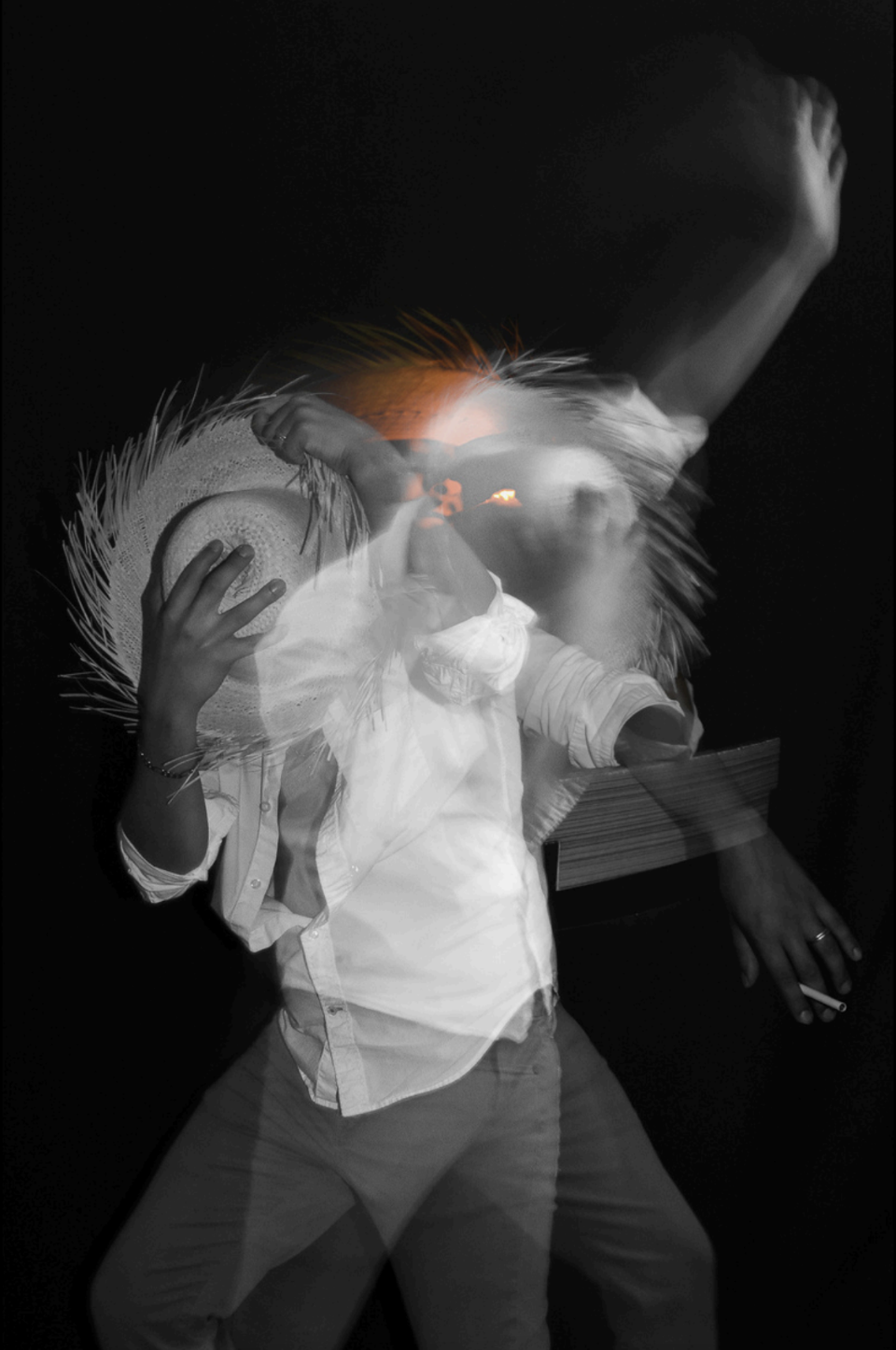 Black and White blurred image of person in straw hat holding a cigarette